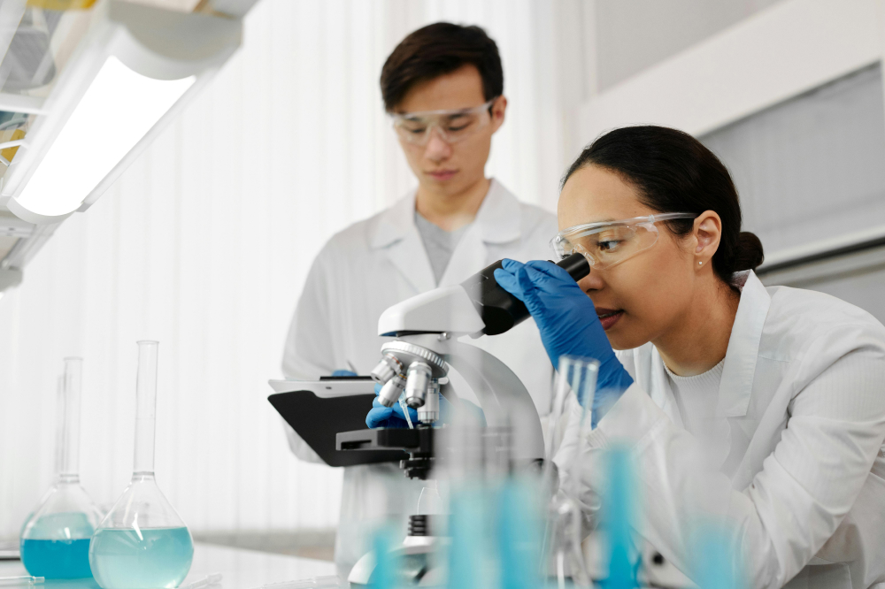 Scientists, a male and female, looking through a microscope